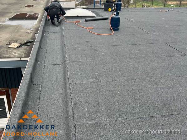 Dakdekker repareert bitumen dakbedekking op groot plat dak in Noord-Holland Dakdekker repareert bitumen dakbedekking op groot plat dak in Noord-Holland